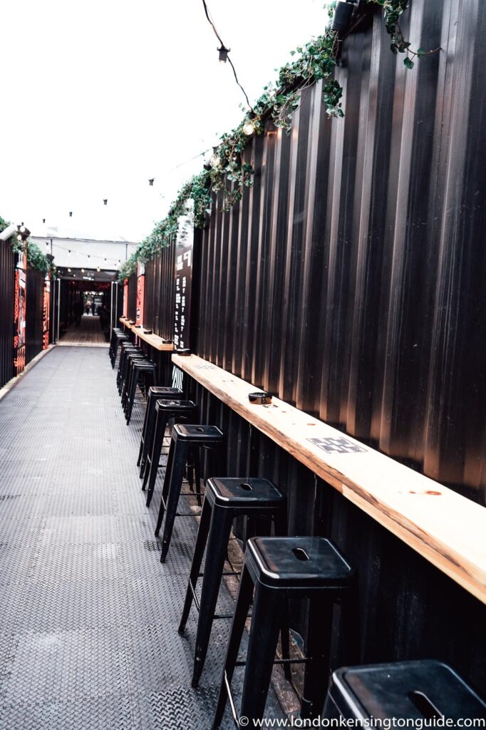 Guide to visiting Boxpark Shoreditch in London. Everything from food, apparel, events, and how to get there. Plus why you should miss it. | Box Park Shoreditch | Boxpark Shoreditch Events | Boxpark Shoreditch Tickets | Black Bear Burger Shoreditch | Boxpark Shoreditch Drinks | Argentinian Grill Boxpark Shoreditch | Rudies Jerk Shack Shoreditch | Boxpark Restaurants Shoreditch | Boxpark Shoreditch London | Boxpark Shoreditch Food | Street Food Shoreditch | Shoreditch Street Food Market